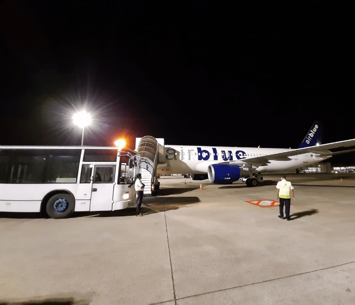 Passenger bus parked next to a plane at the air port.